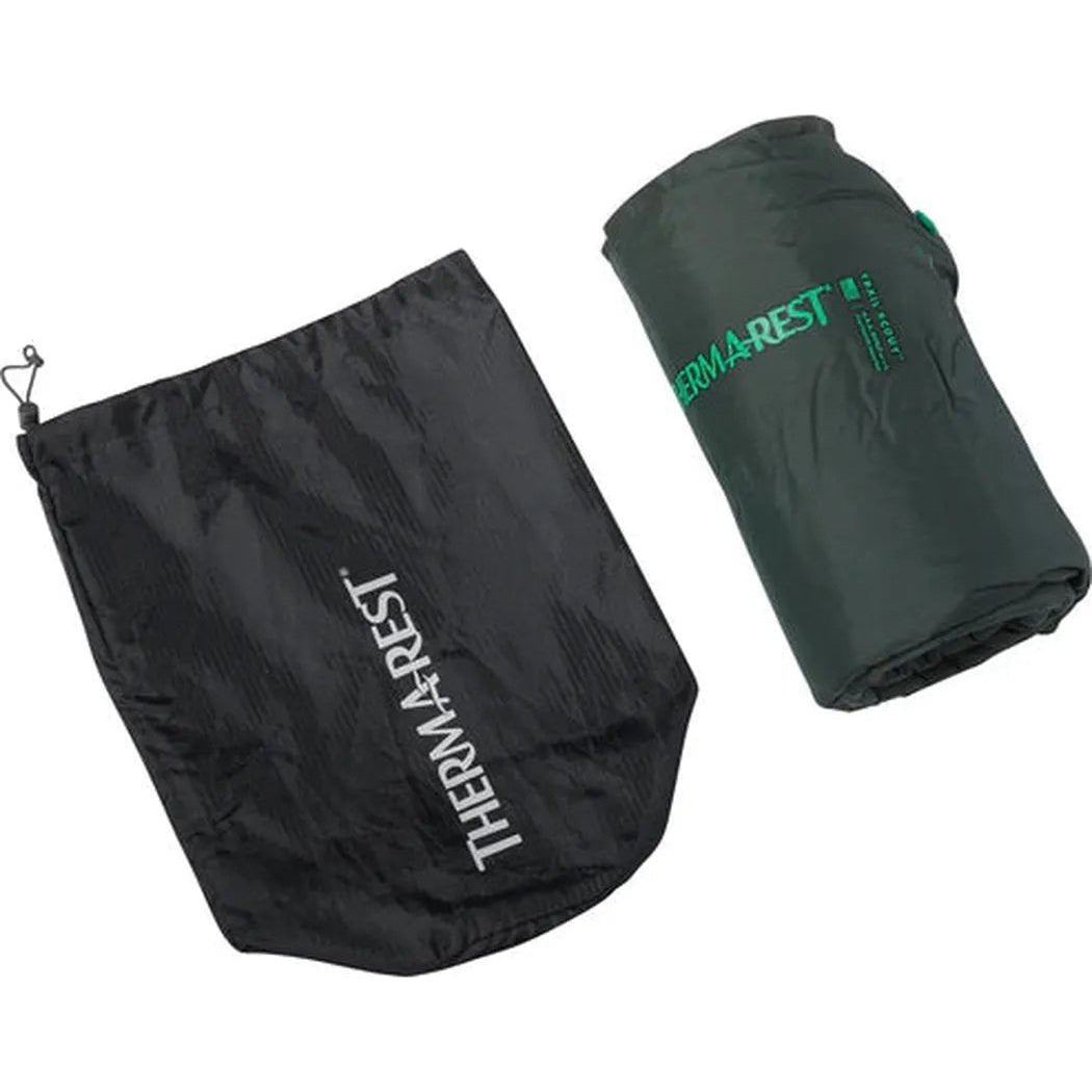 A rolled Therm-a-Rest Trail Scout sleeping pad and its black stuff sack are shown against a white background.
