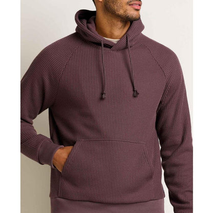 A front view of the Toad & Co Men's Bitterroot Long Sleeve Hoodie in Raisin with a model wearing it against a plain background.