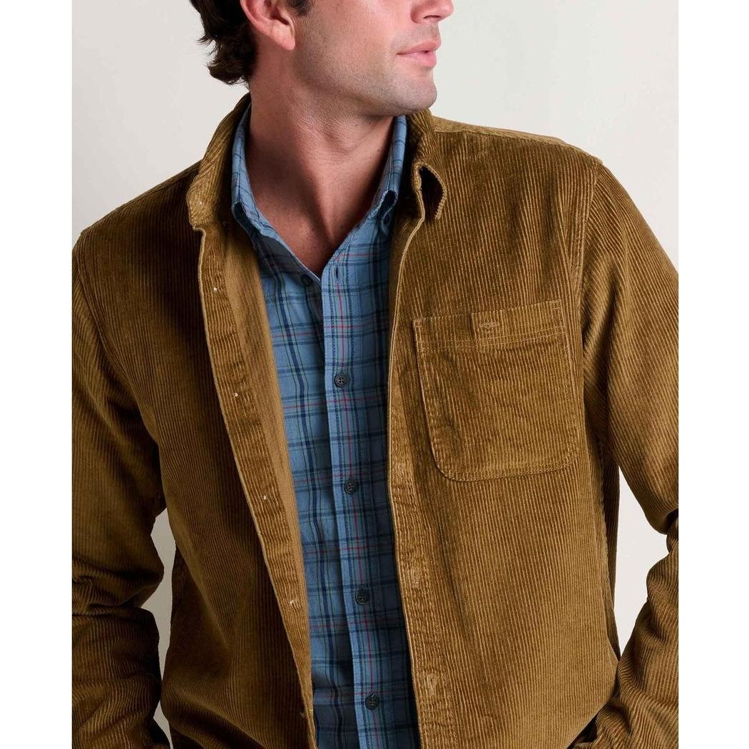 A man wears the Toad & Co Men's Cassadia Long Sleeve Shirt in Honey Brown over a blue plaid shirt, shown from the front with a plain background.