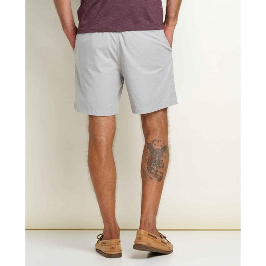 Back view of the Toad & Co Men's Mission Trek Chino Short in Basalt showing the model's tattoo and tan shoes against a plain background.
