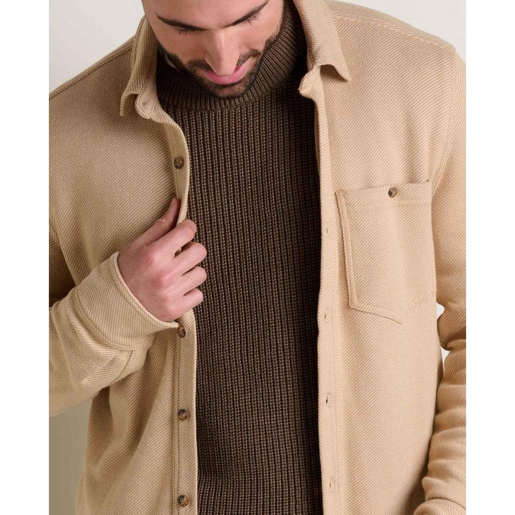 A model wears the Toad & Co Men's Shadowbrook Long Sleeve Shirt in Camel Twill, showing the front pocket and button closure against a neutral background.