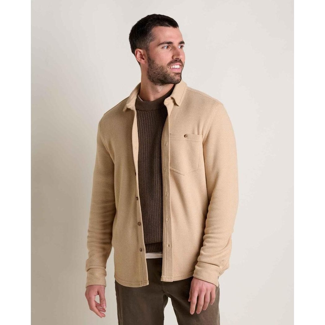 A man wearing the Toad & Co Men's Shadowbrook Long Sleeve Shirt in Camel Twill stands against a plain background.