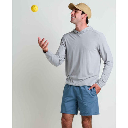 A man wearing the Toad & Co Men's Swifty Long Hoodie in Light Ash tosses a yellow ball against a plain background.