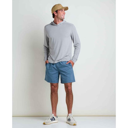 A model wearing the Toad & Co Men's Swifty Long Hoodie in Light Ash stands with hands in pockets against a plain white background.