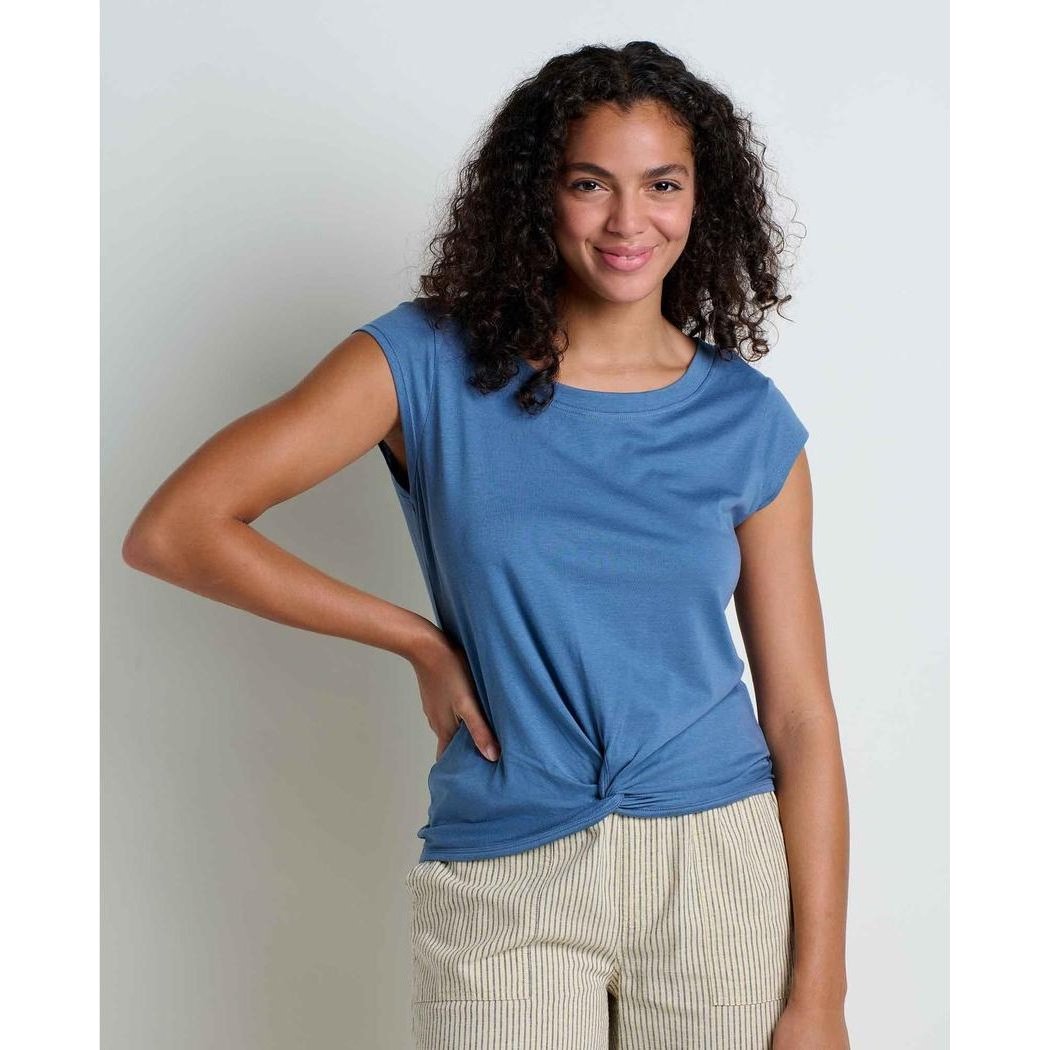 A woman wearing the Toad & Co Women's Anza Short Sleeve Shirt in Pacific Blue poses with one hand on her hip against a plain white background.