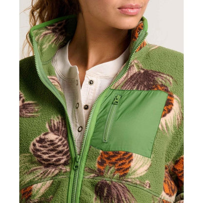 A close-up of the Toad & Co Women's Campo Fleece Jacket in Artichoke Pinecone Print, showing the green zipper and pocket on a model wearing a white henley.