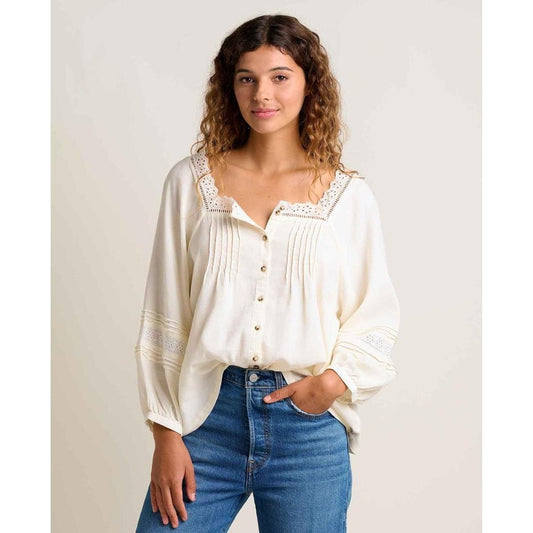 A woman wearing the Toad & Co Women's Manzana Peasant LS Shirt in Egret stands against a plain background.
