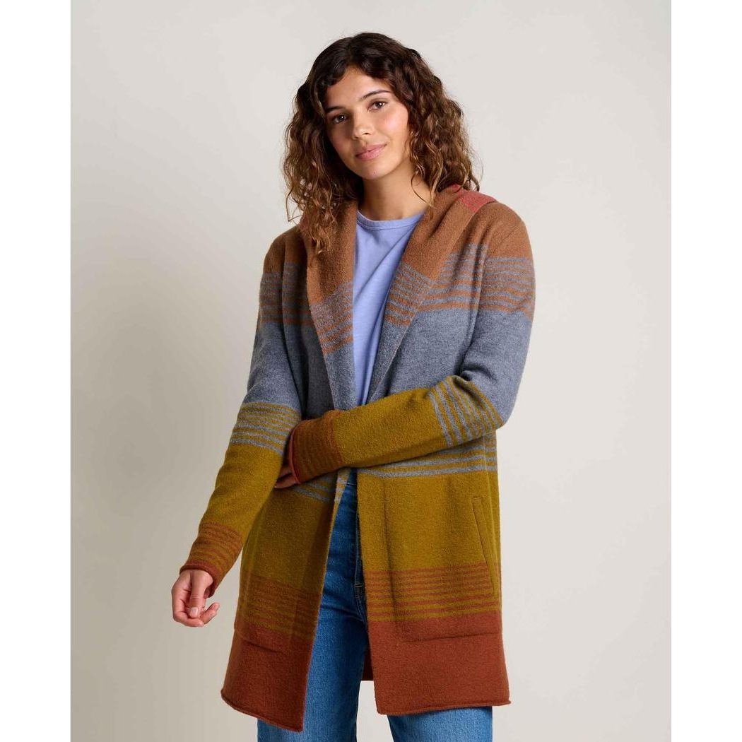 A woman wearing the Toad & Co Women's Merino Heartfelt Hoodie in Coyote Ombre stands against a plain background.