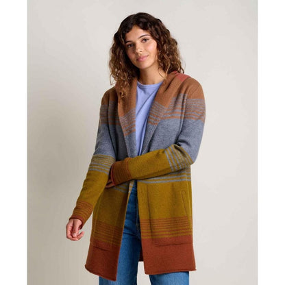 A woman wearing the Toad & Co Women's Merino Heartfelt Hoodie in Coyote Ombre stands against a plain background.