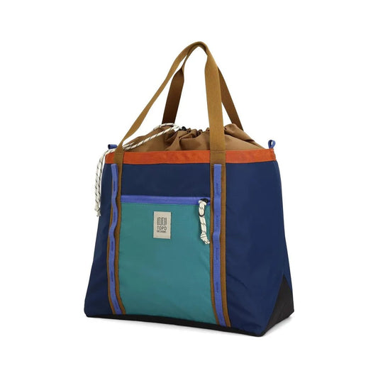 A front view of the Topo Designs Mountain Utility Tote in Forest / Bone White with a front pocket and brown straps against a white background.