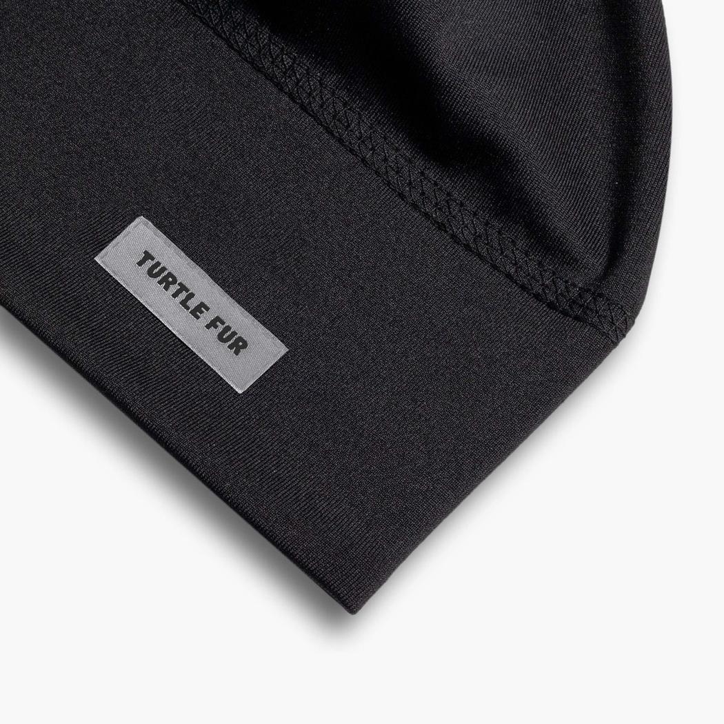 A close-up of the black Turtle Fur Comfort Shell Brain Shroud showing the label and stitching.