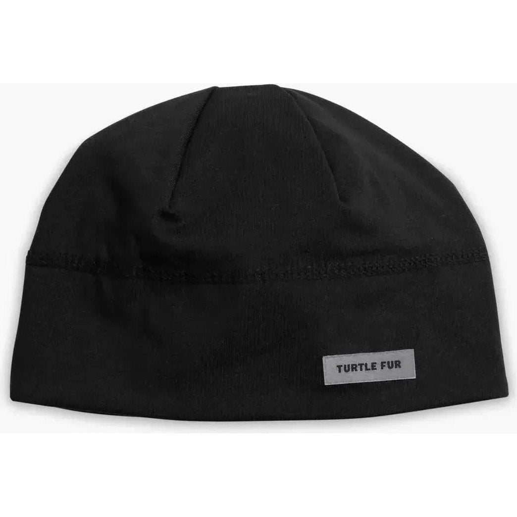 A front view of the black Turtle Fur Comfort Shell Brain Shroud hat with a label on the front against a white background.