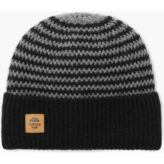 A front view of the Turtle Fur Lambswool Gus hat in Black with a ribbed cuff and a leather tag, set against a plain white background.