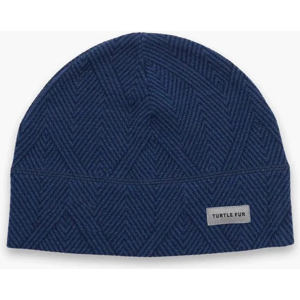 A front view of the Turtle Fur Men's Carefree Merino Wool Beanie in Diagonal Stride with a label on the front.
