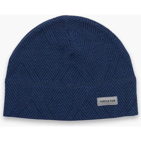 A front view of the Turtle Fur Men's Carefree Merino Wool Beanie in Diagonal Stride with a label on the front.