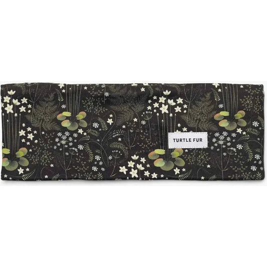 A flat lay photo of the Turtle Fur Women's Comfort Shell adjustable wide bandana in Marsha, showing the floral pattern and the brand label.