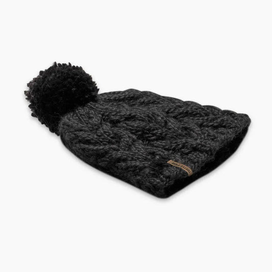 A black Turtle Fur Women's Merino Wool Millie hat with a pom pom, shown from a side angle against a white background.