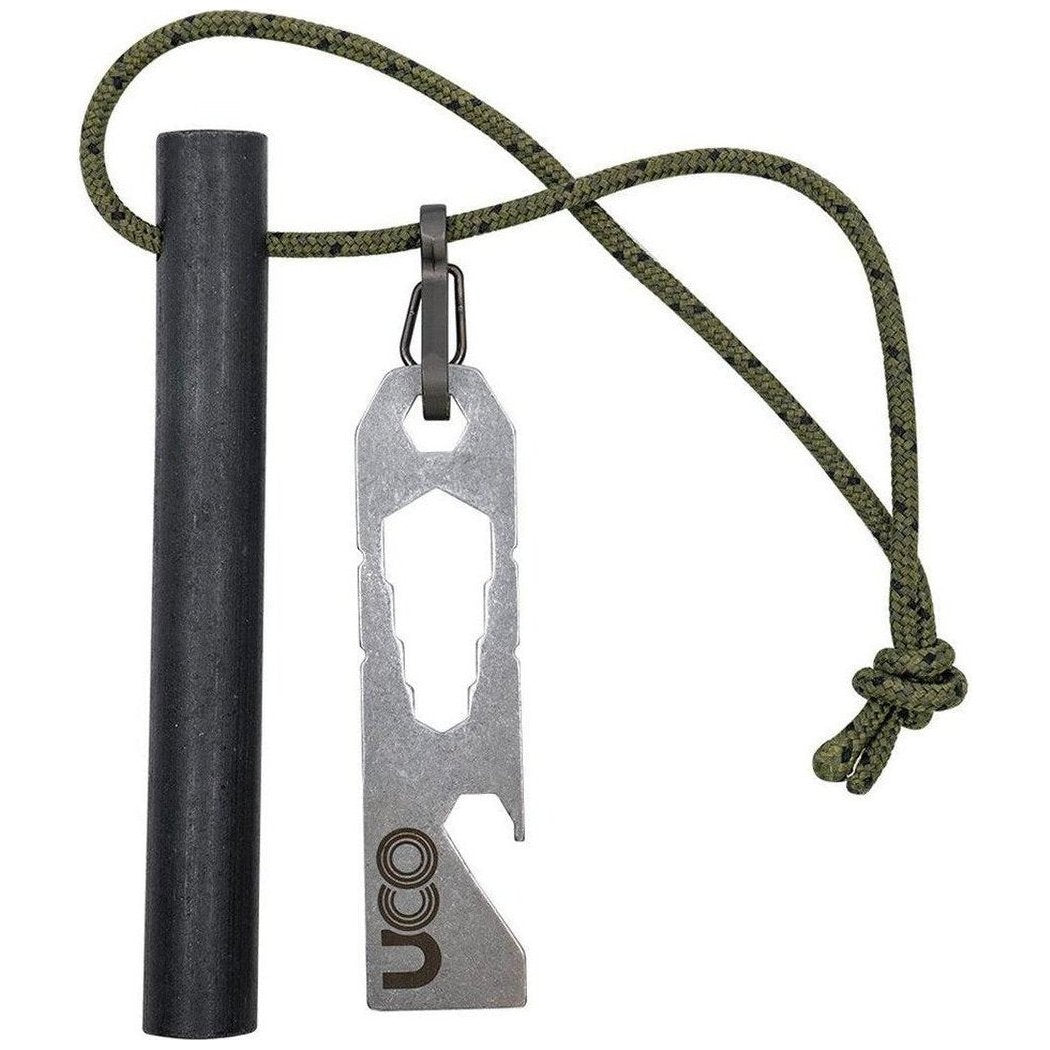 A charcoal ferro rod and UCO Titan Fire Striker hang from a green paracord against a white background.