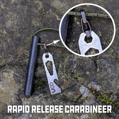 A close-up of the UCO Titan Fire Striker - Ferro Rod with its rapid release carabiner, shown on a rocky surface.