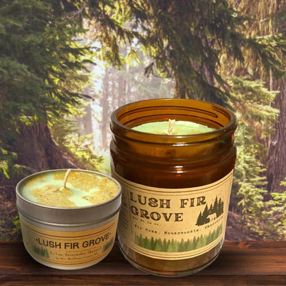 Two Lush Fir Grove candles sit on a wooden surface with a forest background.