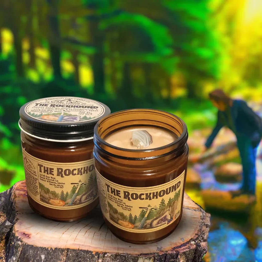 Two 4 oz The Rockhound candles sit on a tree stump with a forest background.
