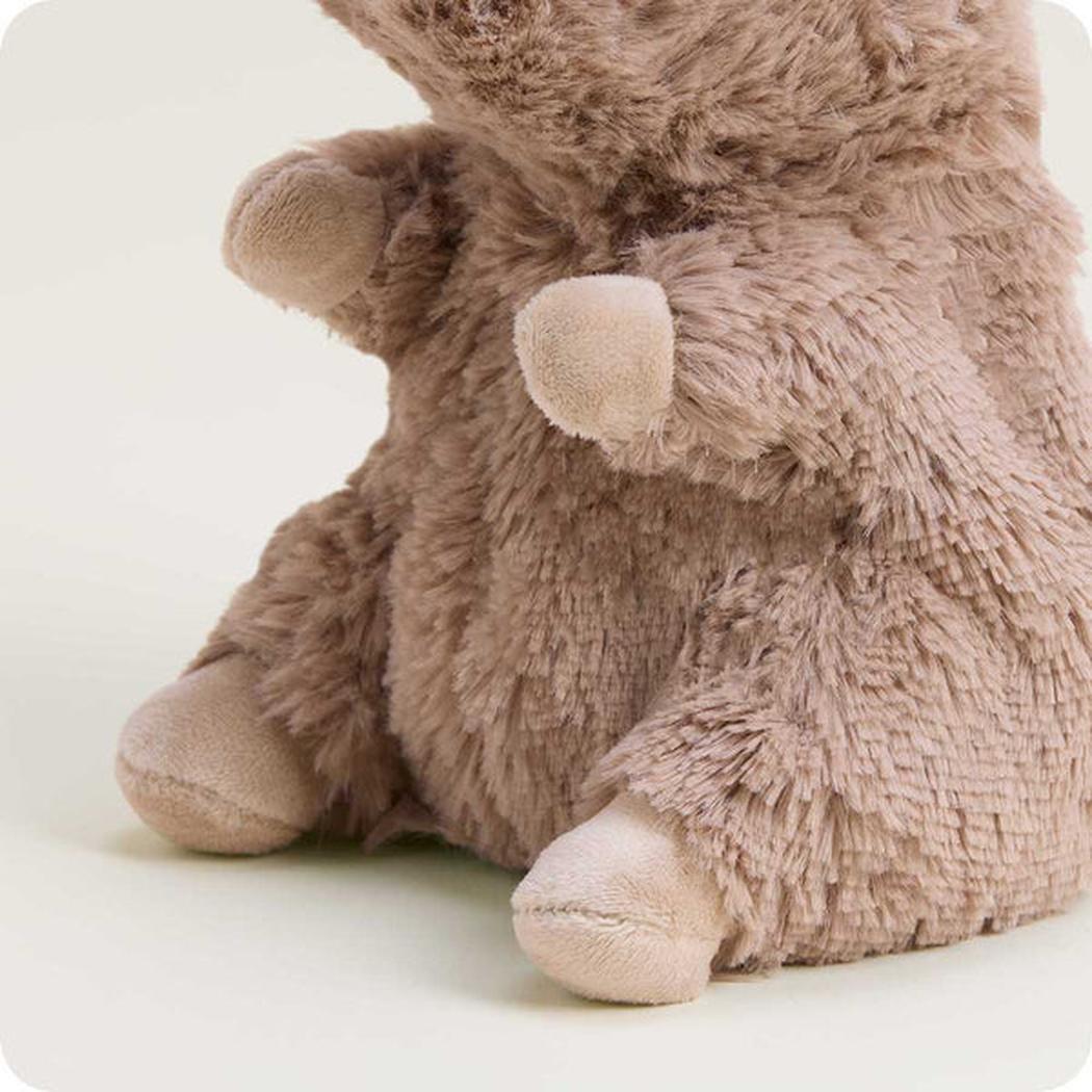 A close-up of the Warmies Capybara Junior plush toy showing its soft fur and light-colored paws against a plain background.