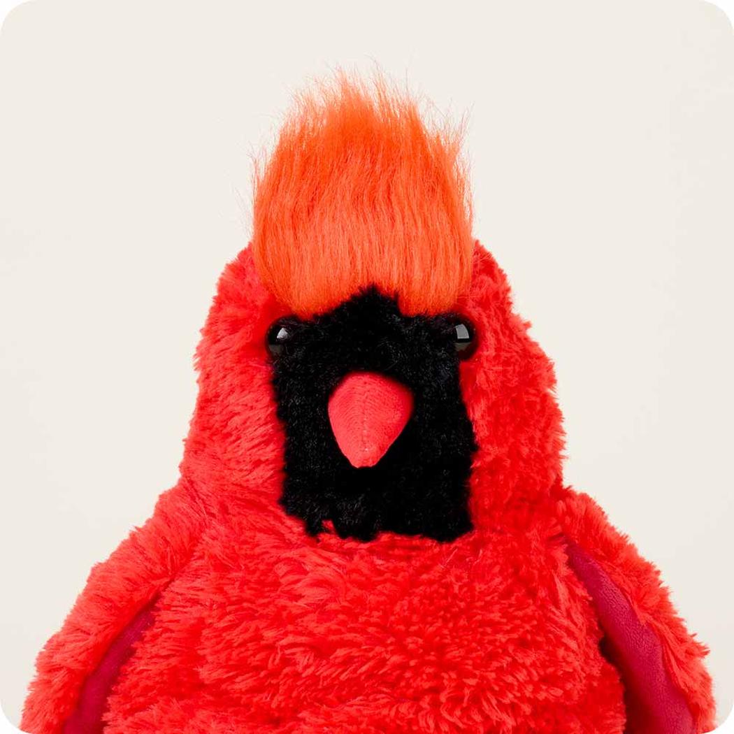 A front view of the Warmies Cardinal plush toy with bright orange mohawk and black face against a plain white background.
