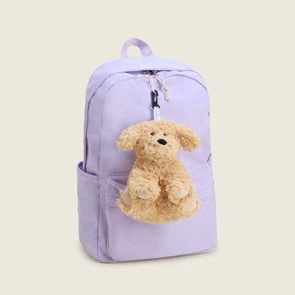 A light purple backpack with a Warmies Curly Dog Bag Charm hanging from the zipper, set against a plain background.