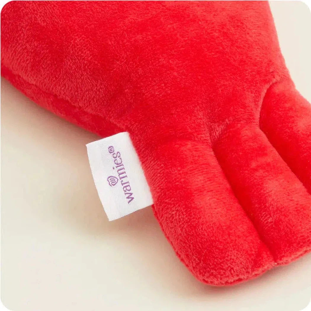 A close-up of the red Warmies Lobster showing the brand tag and soft plush texture against a light background.