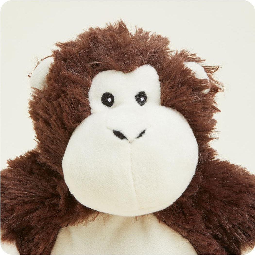 A close-up of the Warmies Monkey Junior plush toy with brown fur and a white face against a plain background.