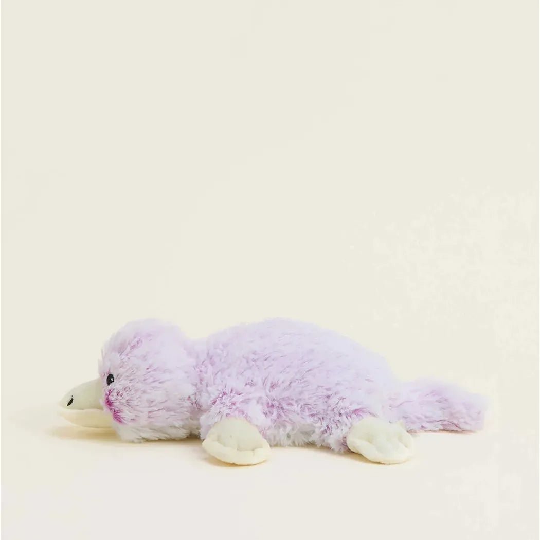 A side view of the Warmies Platypus Warmies Junior stuffed animal with a light purple body and white feet against a plain white background.