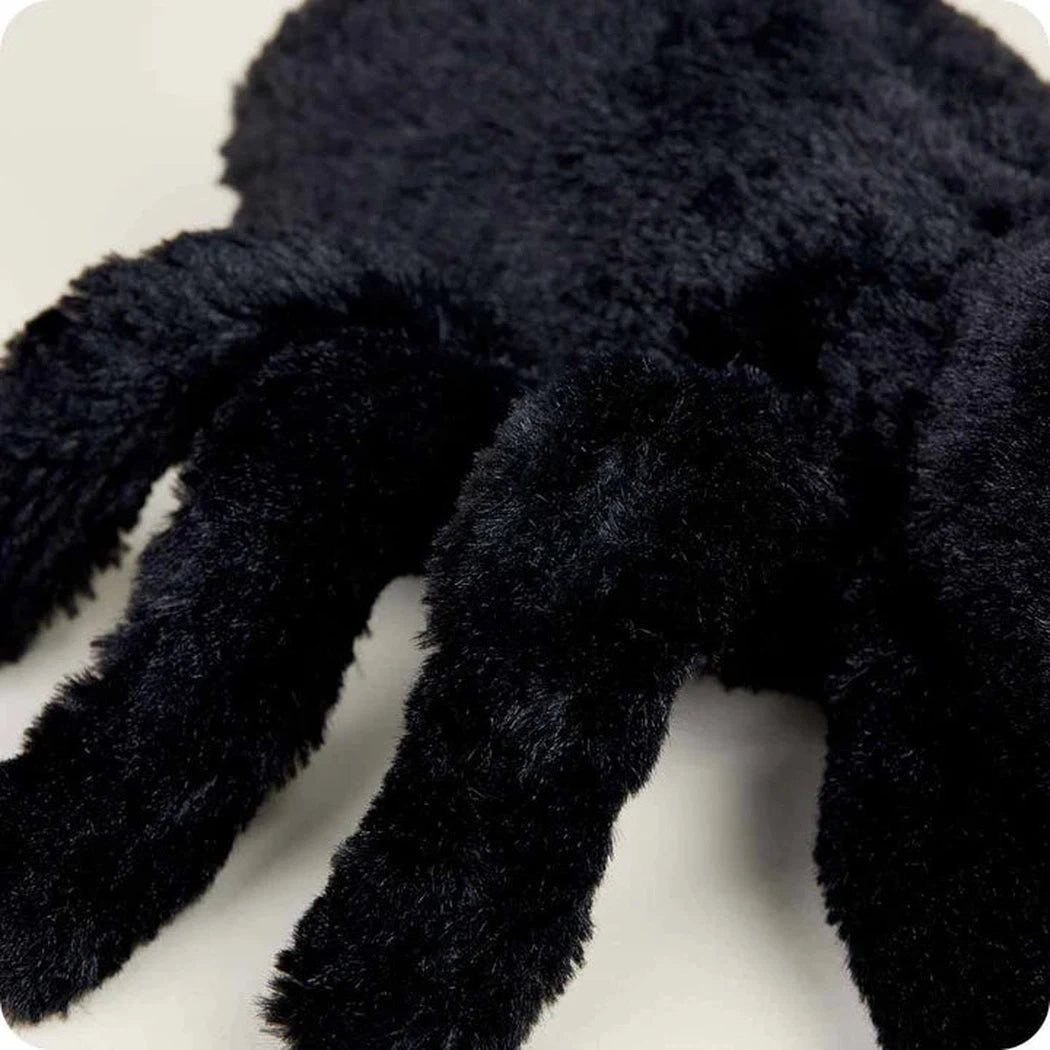 A close-up of the Warmies Spider showing its fuzzy legs and dark color against a light background.