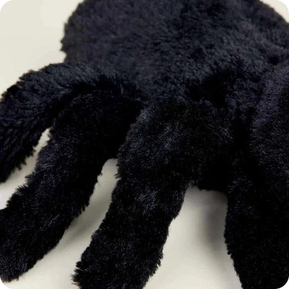A close-up of the Warmies Spider showing its fuzzy legs and dark color against a light background.