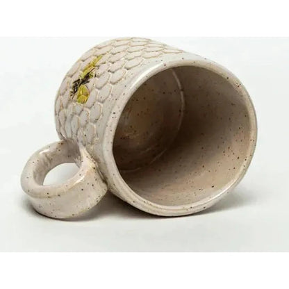 A side view of the White Squirrel Clayworks Bee Pattern Handmade in Ohio Ceramic White 10 oz Mug showing the textured exterior and open interior against a white background.