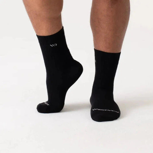 Side view of the Wide Open Men's Solid Cushioned Micro Crew Socks in Black on a model against a white background.