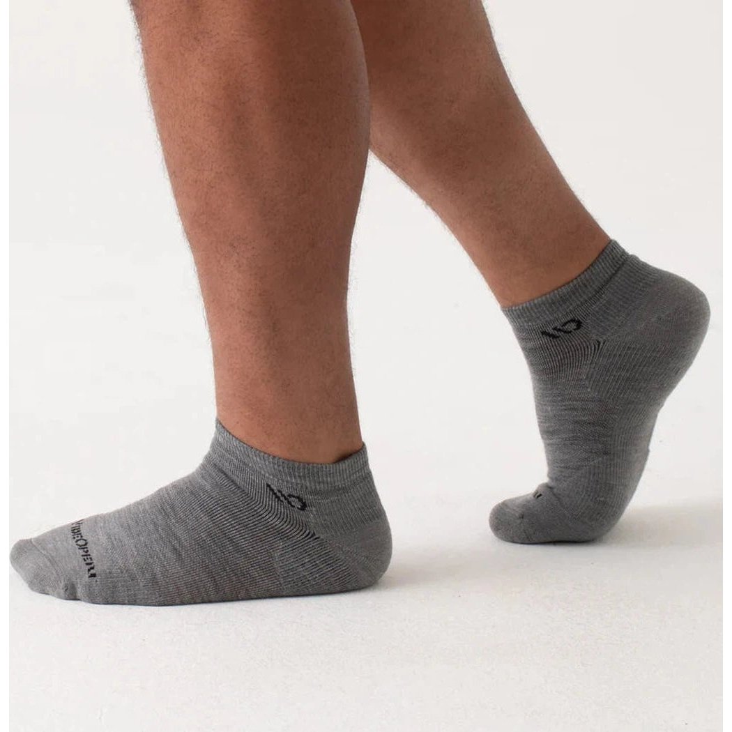 A close-up of a man wearing Wide Open Men's Solid Midweight No Show Socks in Denim, showing the ankle and foot against a plain white background.