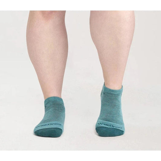 A woman wearing Charcoal Wide Open Women's Solid Midweight No Show Socks stands against a white background.