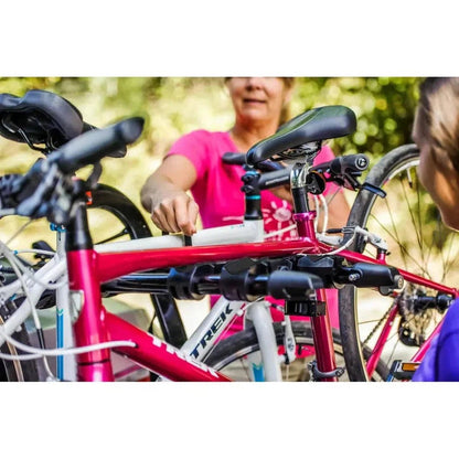 A woman adjusts the red Yakima FullBack bike rack in a sunny outdoor setting with green foliage in the background.