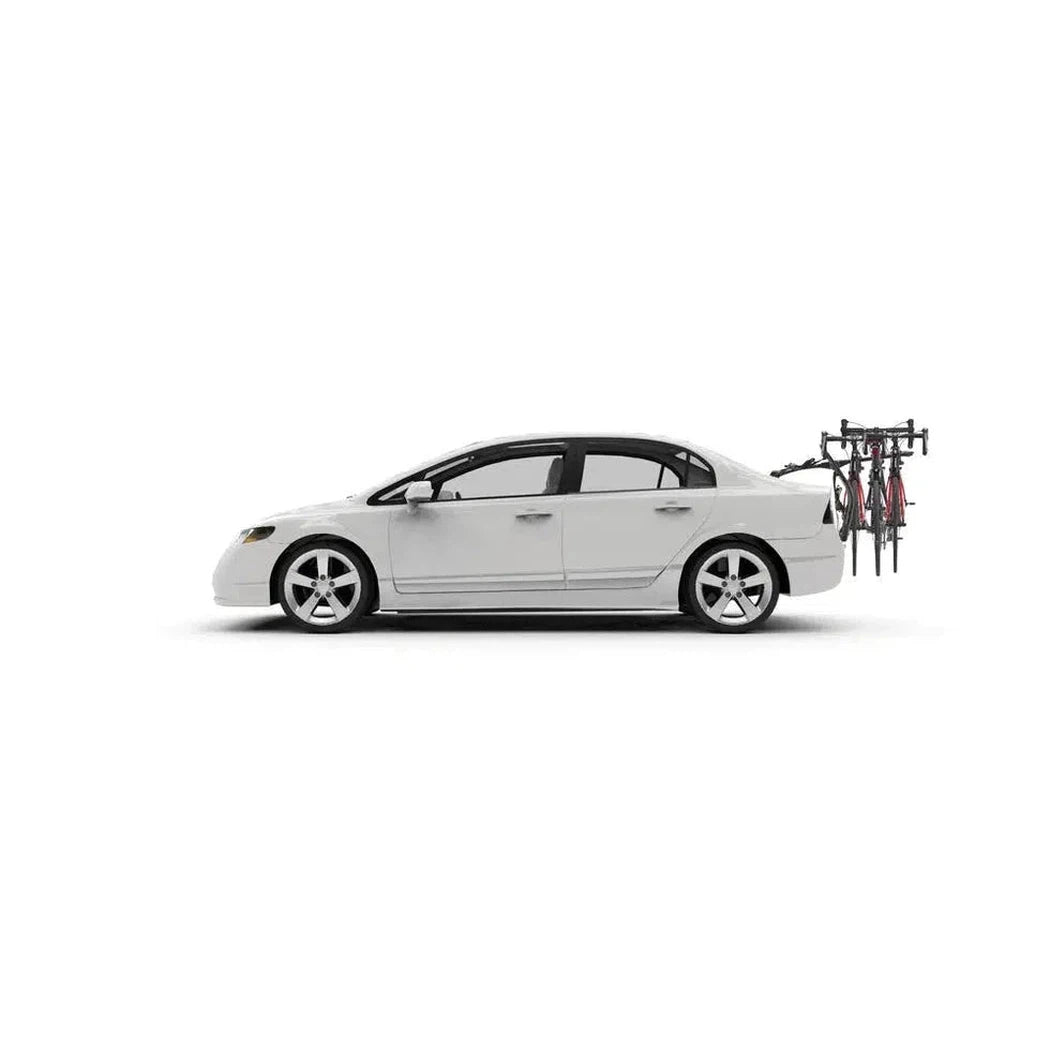 Side view of the Yakima FullBack 2 car rack with two bikes mounted on the back of a white sedan against a plain white background.