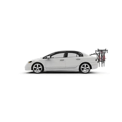 Side view of the Yakima FullBack 2 car rack with two bikes mounted on the back of a white sedan against a plain white background.