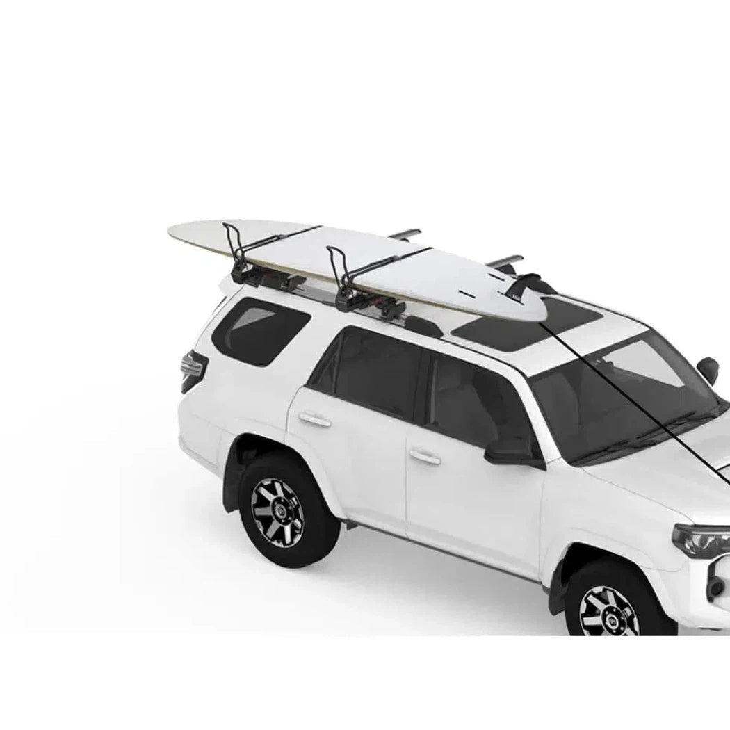 A white SUV with a Yakima Showdown car rack holding a surfboard, photographed from a three-quarter angle against a white background.